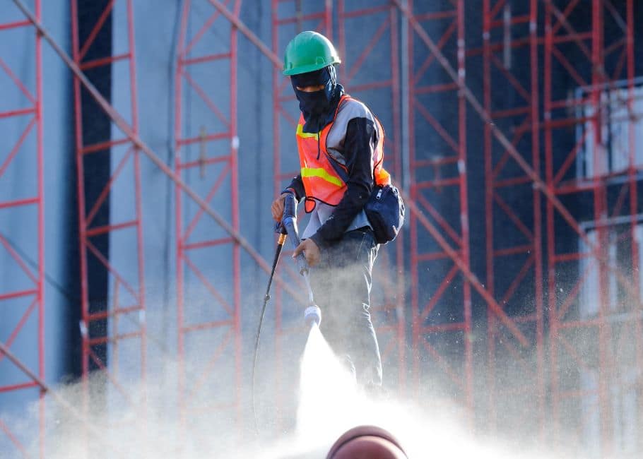 Cleaning worker spraying water on site